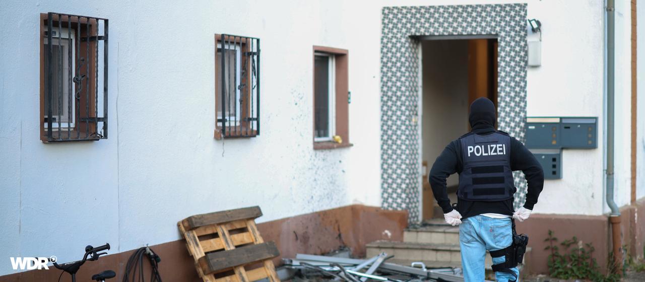 Ein Polizeibeamter steht im Rahmen einer Razzia gegen die Hells Angels vor einem Wohnhaus in Langenfeld