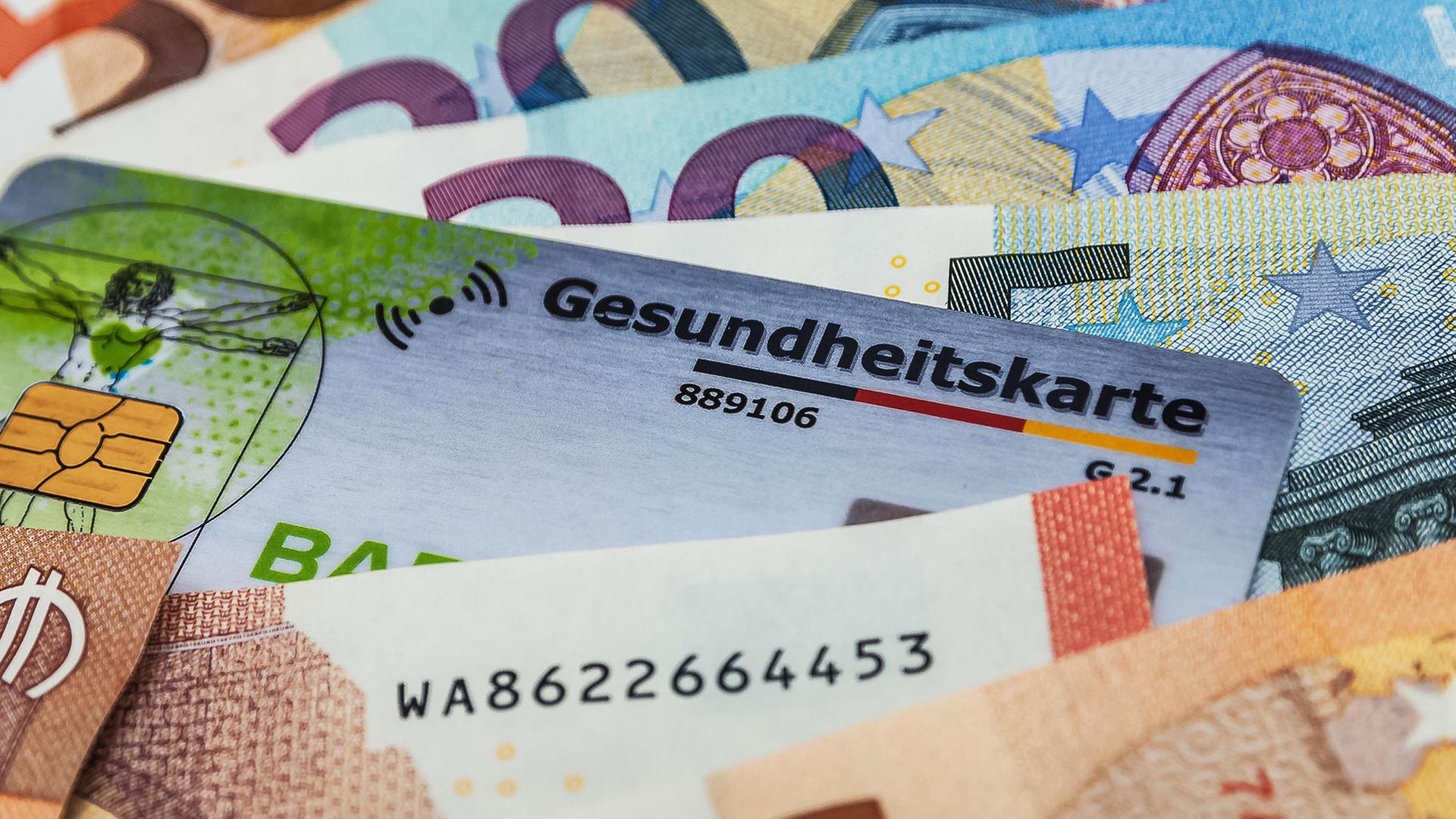 Eine Gesundheitskarte zwischen Geldscheinen. | picture alliance / Zoonar