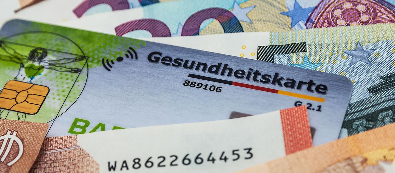 Eine Gesundheitskarte zwischen Geldscheinen.
