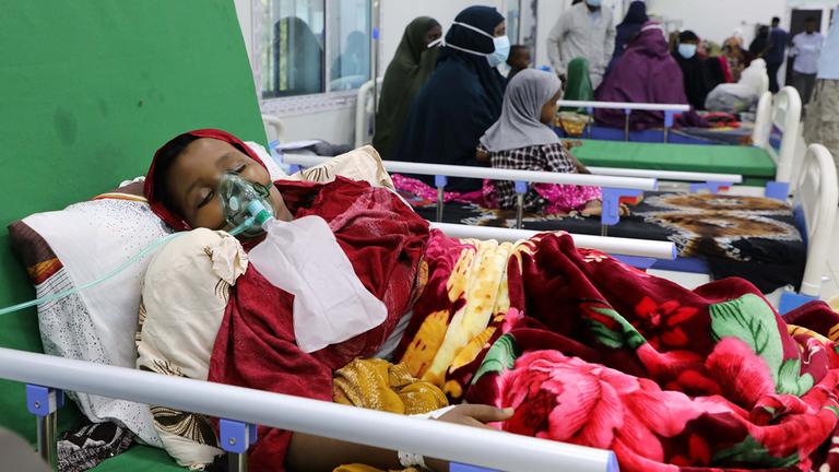 Ein Kind liegt in einem Krankenbett und trägt eine Beatmungsmaske.