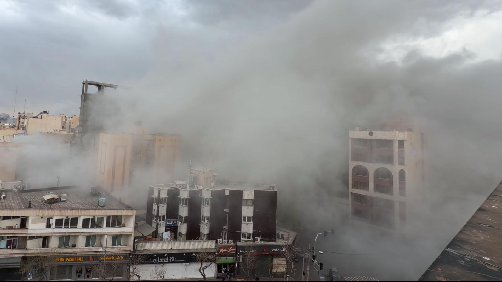 Eine Straße voller Rauch nach einer Explosion in Teheran. | Mohsen Ganji/AP/dpa