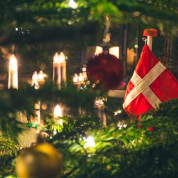 Ein Weihnachtsbaum von nahmen, mit Kerzen, Kugeln und einer Dänemarkflagge geschmückt.
