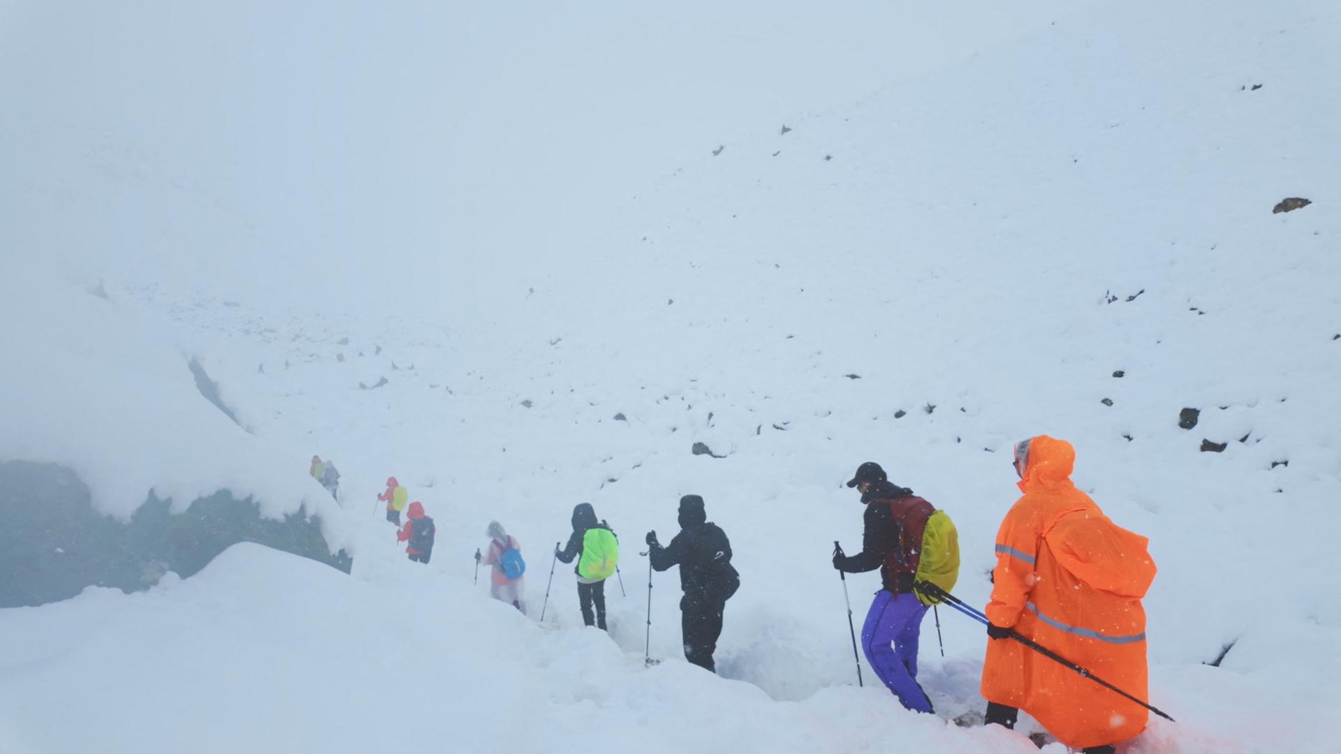 Ein Screenshot aus einem Video zeigt Wanderer, die ihren Lagerplatz verlassen, als ungewöhnlich starker Schneefall und Regen den Himalaya in der Region Tibet in China heimsuchten. | via REUTERS