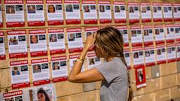 Eine Frau schaut sich Fotos mit den Geiseln der Hamas an einer Häuserwand in Tel Aviv an.