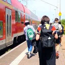 Fahrgäste laufen am Bahnhof Schwerin-Süd neben einem Regionalexpress.