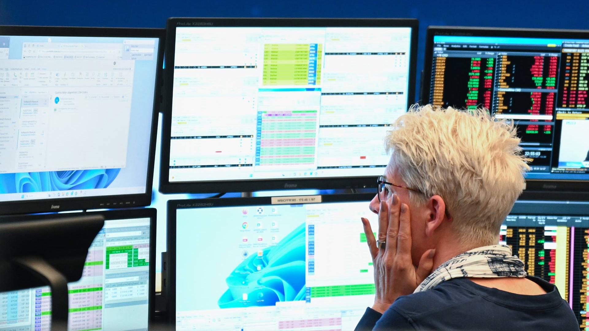 Eine Händlerin an der Börse Frankfurt sitzt vor Bildschirmen. | picture alliance/dpa