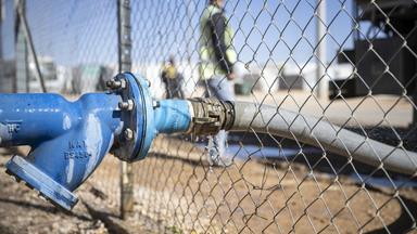  Wasser wird per Schlauch in eine Wasserstation im Saatari Flüchtlingscamp gefüllt.