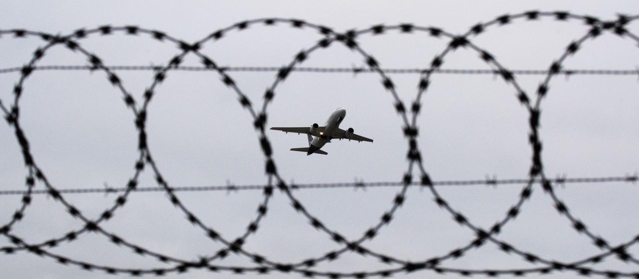 Ein Passagierflugzeug startet hinter einer Stacheldrahtabsperrung.