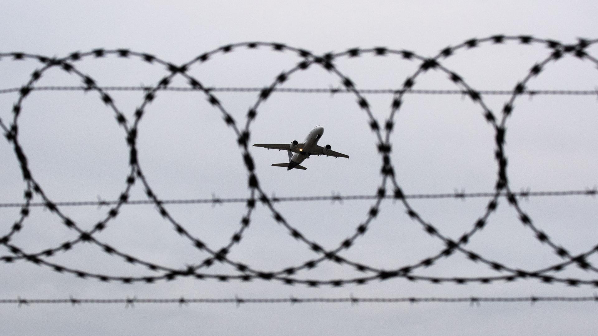 Ein Passagierflugzeug startet hinter einer Stacheldrahtabsperrung. | dpa