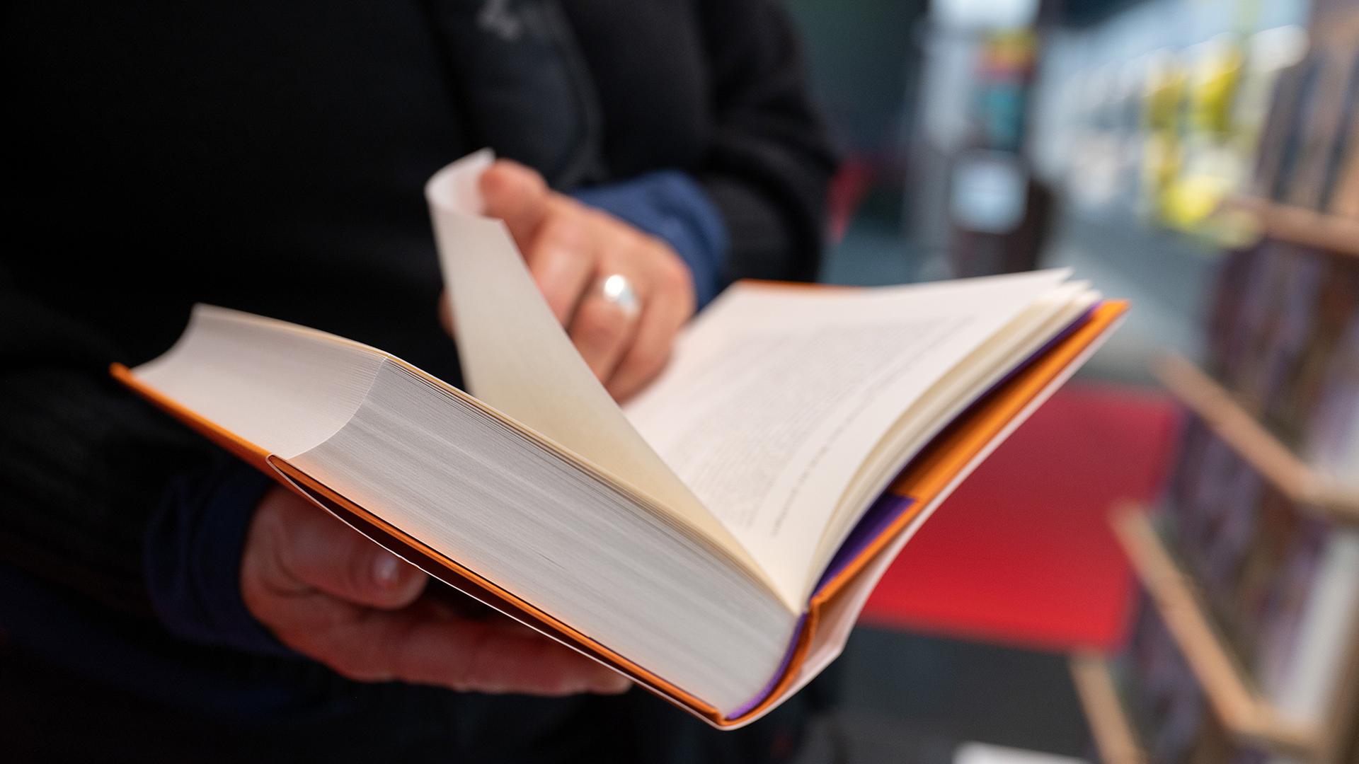 Eine Frau blättert in einem Buch. | picture alliance/dpa
