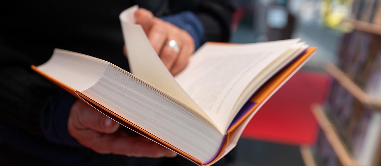 Eine Frau blättert in einem Buch.