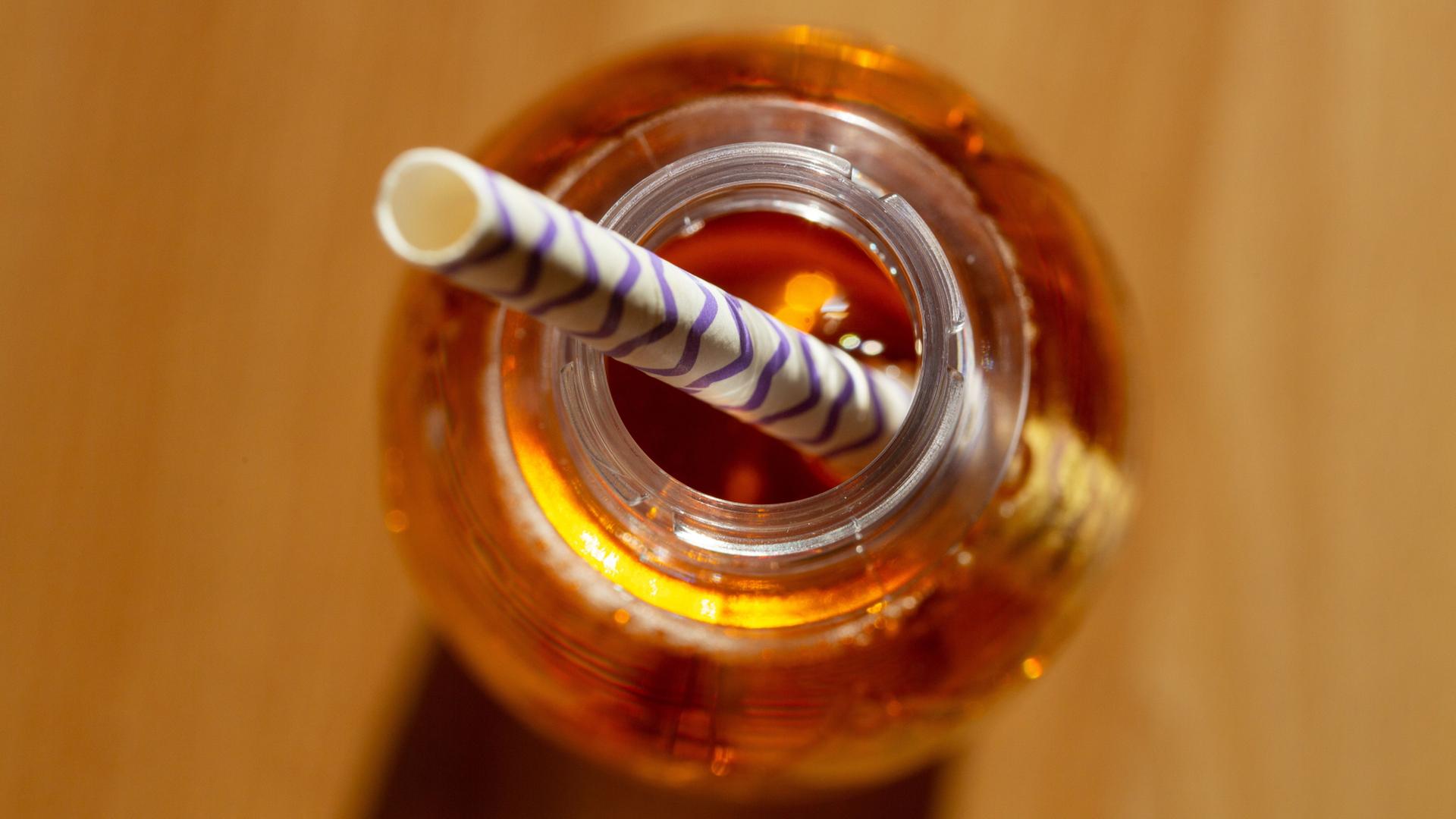 Eine geöffnete Flasche mit einem zuckerhaltigen Erfrischungsgetränk mit einem Trinkhalm steht auf einem Tisch. | Fernando Gutierrez-Juarez/dpa