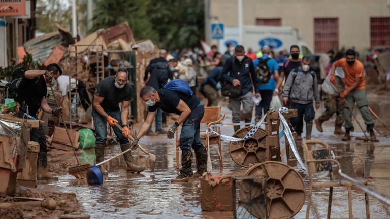 Menschen räumen nach den Überschwemmungen in der Provinz Valencia auf.