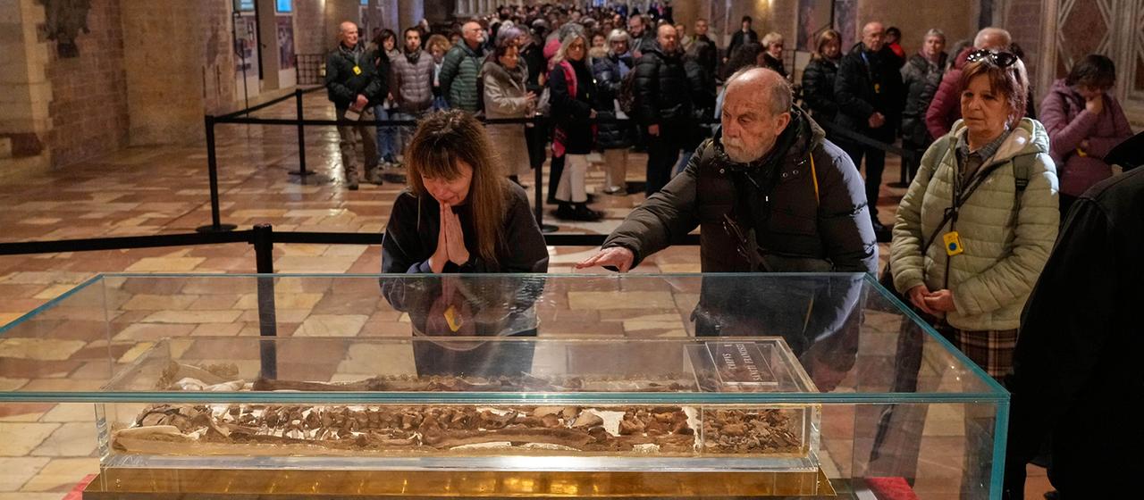 Besucher einer Kirche betrachten Reliquien in einem Glaskasten.