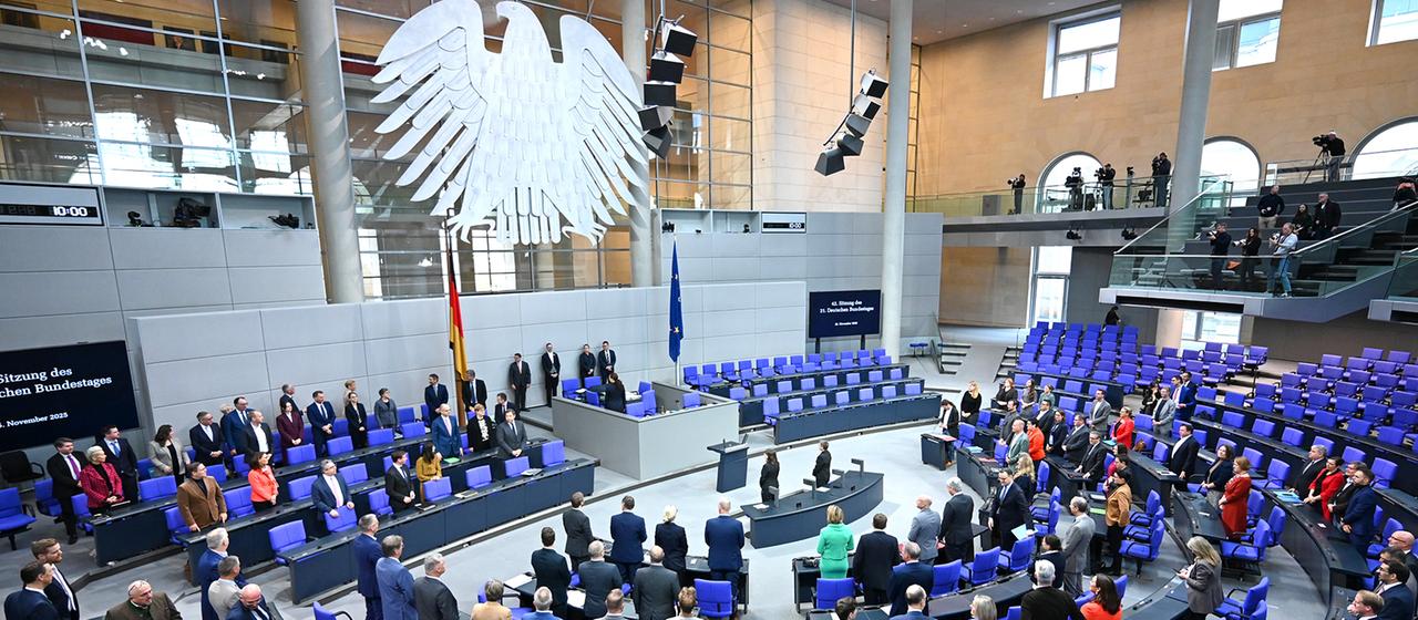 Abgeordnete stehen zu Beginn der 42. Plenarsitzung der 21. Legislaturperiode im Deutschen Bundestag.