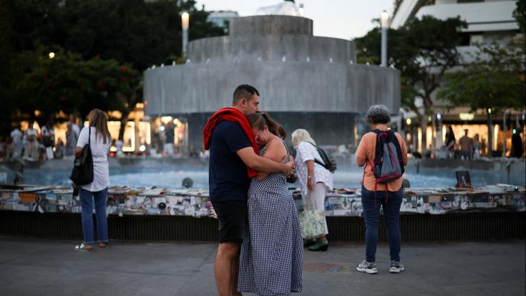 Ein Mann und eine Frau umarmen sich vor einem Brunnen in Tel Aviv am 7. Oktober 2026.