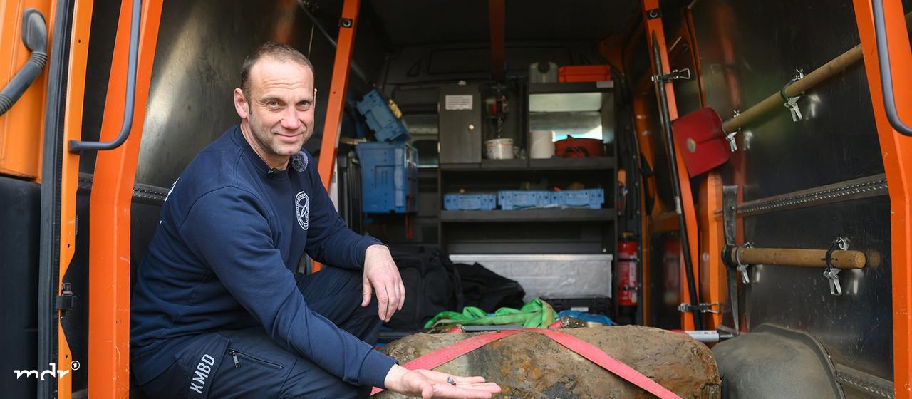 Ein Sprengmeister von der Kampfmittelbeseitigung hockt nach der Entschärfung einer Weltkriegsbombe mit dem Rest des Zünders neben der Bombe