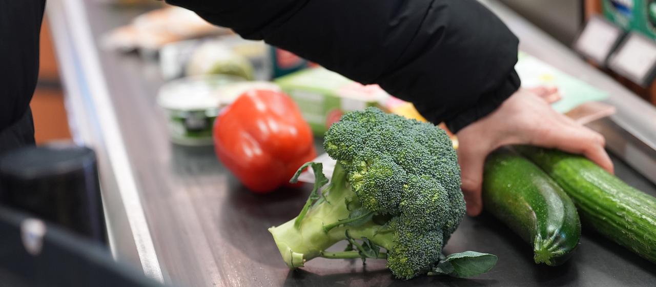 Ein Mann legt seinen Einkauf auf das Laufband an einer Kasse in einem Supermarkt.
