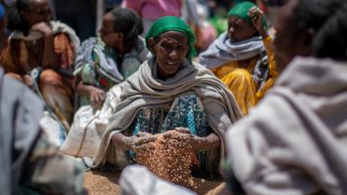 Einer Frau in Tigray rinnt eine Getreideration aus einer Hilfslieferung durch die Hände.