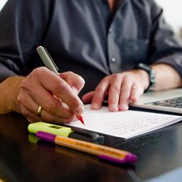 Ein Mann sitzt im Homeoffice am Tisch an einem Laptop und arbeitet.