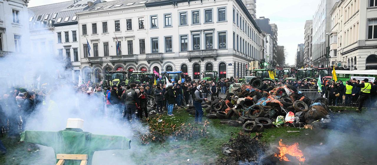 Protestierende Landwirte stehen neben Traktoren und einem Feuer in der Nähe des Europäischen Parlaments auf der Place du Luxembourg in Brüssel.