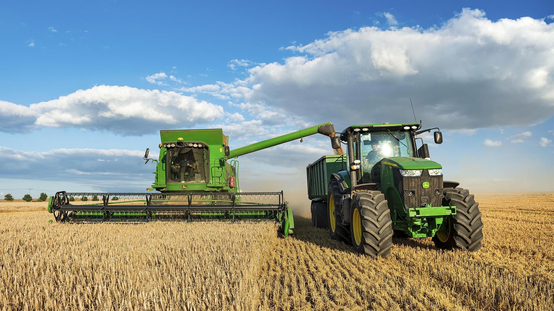 Mähdrescher erntet Weizen und entlädt Getreide auf Traktor mit Anhänger. | picture alliance / imageBROKER