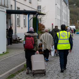 Neuangekommene Flüchtlinge gehen mit ihren Koffern in eines der Wohnhäuser der Aufnahmeeinrichtung für Asylbegehrende in Trier.