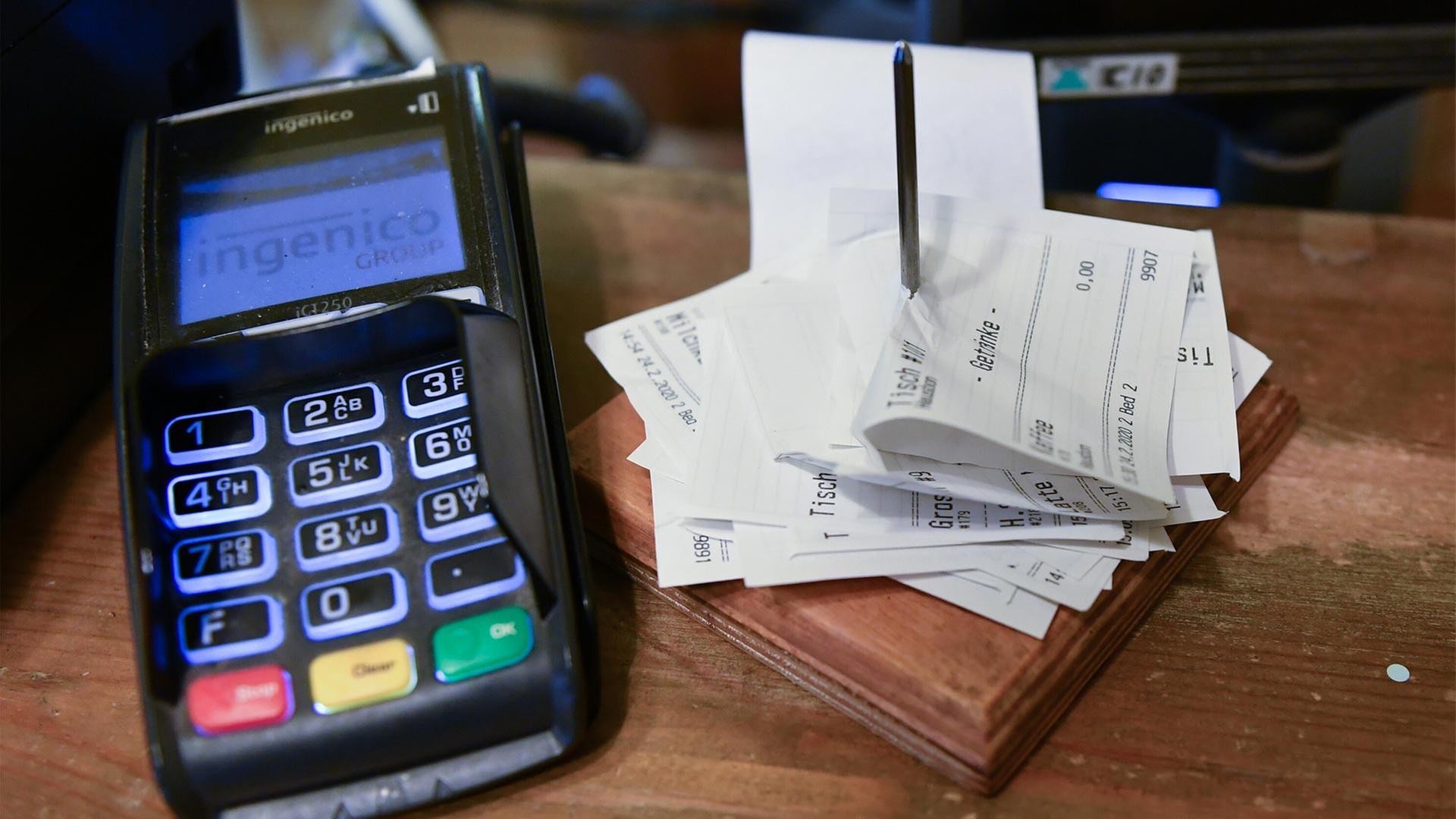 Neben einem EC-KartenlesegerÃ¤t sind in einem CafÃ© Kassenbons aufgespieÃt. | picture alliance/dpa/dpa-Zentral