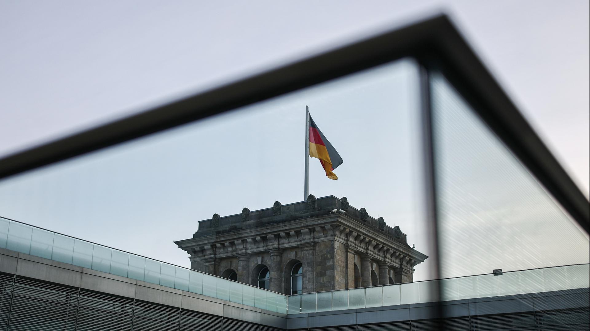 Eine Deutschland-Fahne weht über einem Turm des Reichstagsgebäudes. | dpa