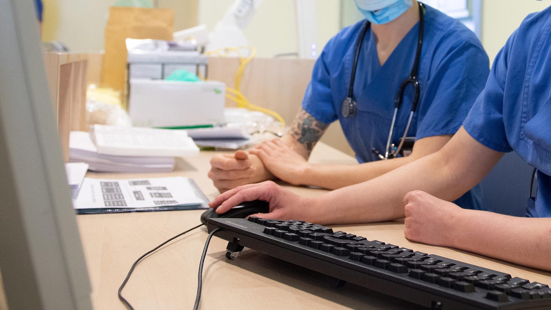 Ärzte sitzen vor einem Computerbildschirm.  | dpa