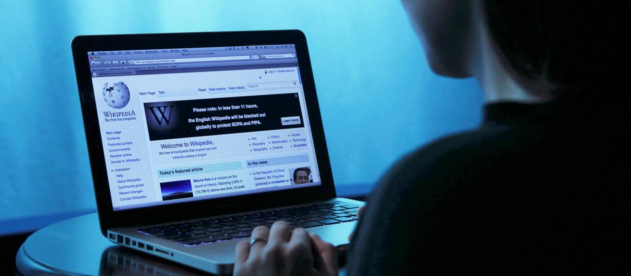 Eine Frau schaut auf einen Laptop, auf dem die Internetseite Wikipedia geöffnet ist. | REUTERS Eine Frau schaut auf einen Laptop, auf dem die Internetseite Wikipedia geöffnet ist.