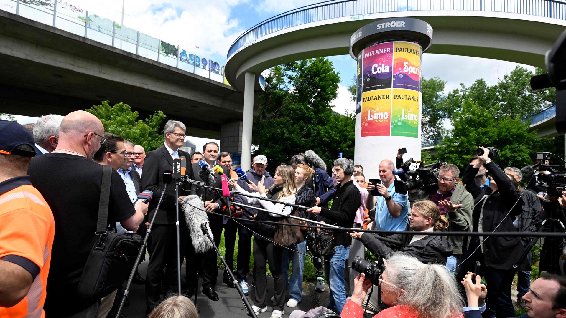 Patrick Schnieder spricht umringt von Menschen an einer Brücke in Mikrofone | AFP