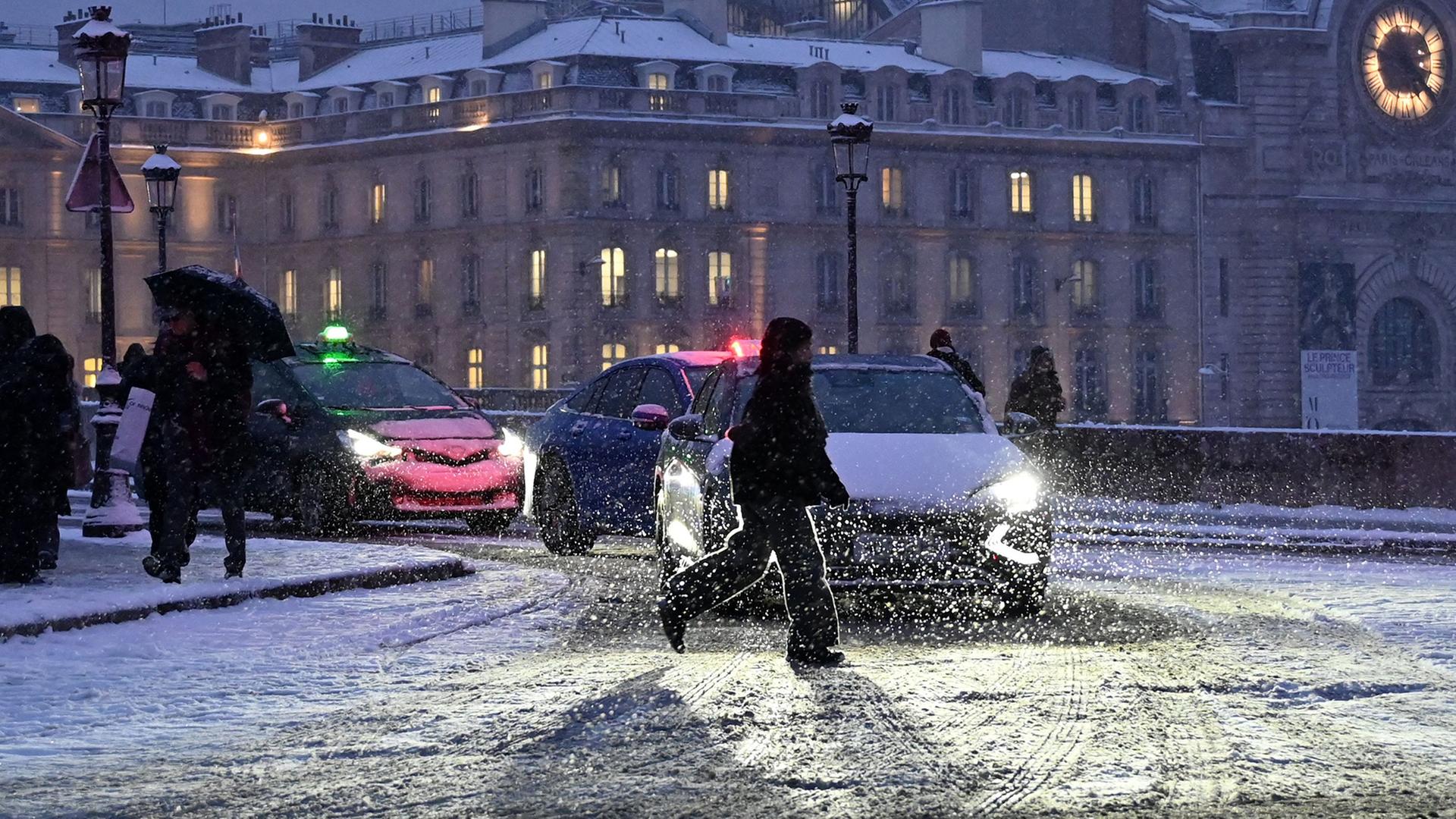 Ein Fußgänger überquert eine mit Schnee bedeckte Straße in der Nähe von Point Royal in Paris. | AFP