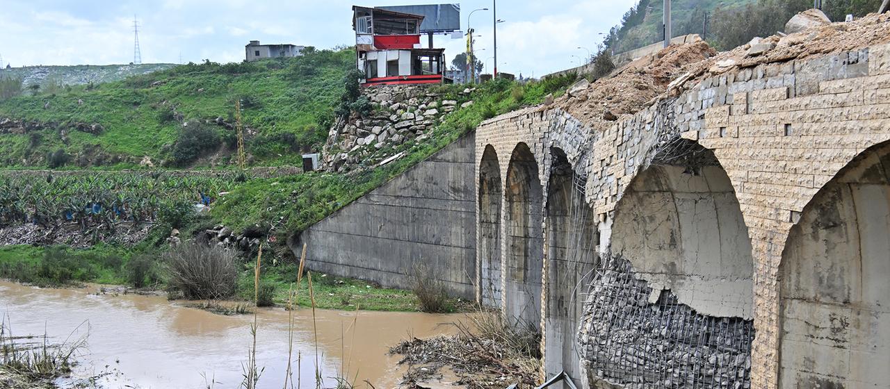 Blick auf eine zerstörte Brücke, die über einen Fluss führt.