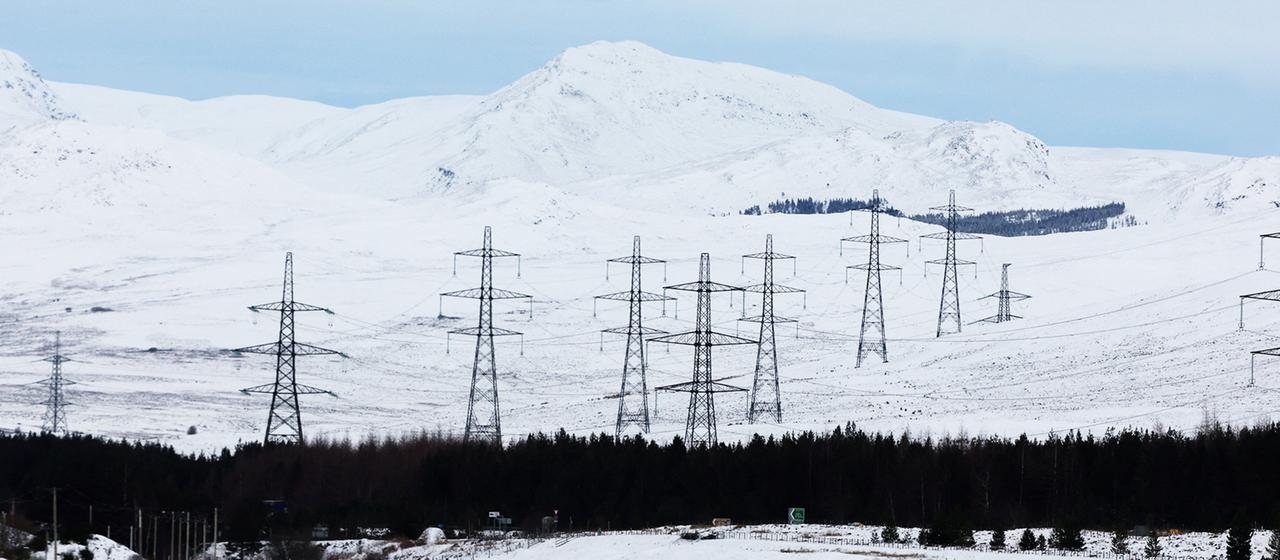 Strommasten stehen in verschneiter Landschaft bei Dalwhinnie, Schottland