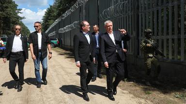 Tomasz Siemoniak (Mitte rechts) und Alexander Dobrindt gehen am Grenzzaun an der polnisch-belarusischen Grenze entlang.