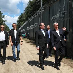 Tomasz Siemoniak (Mitte rechts) und Alexander Dobrindt gehen am Grenzzaun an der polnisch-belarusischen Grenze entlang.