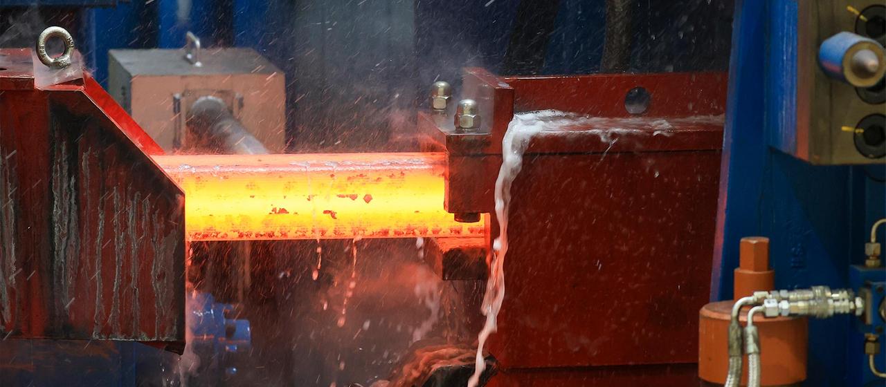 Ein noch glühender Knüppel Stahl fährt ins Walzwerk.