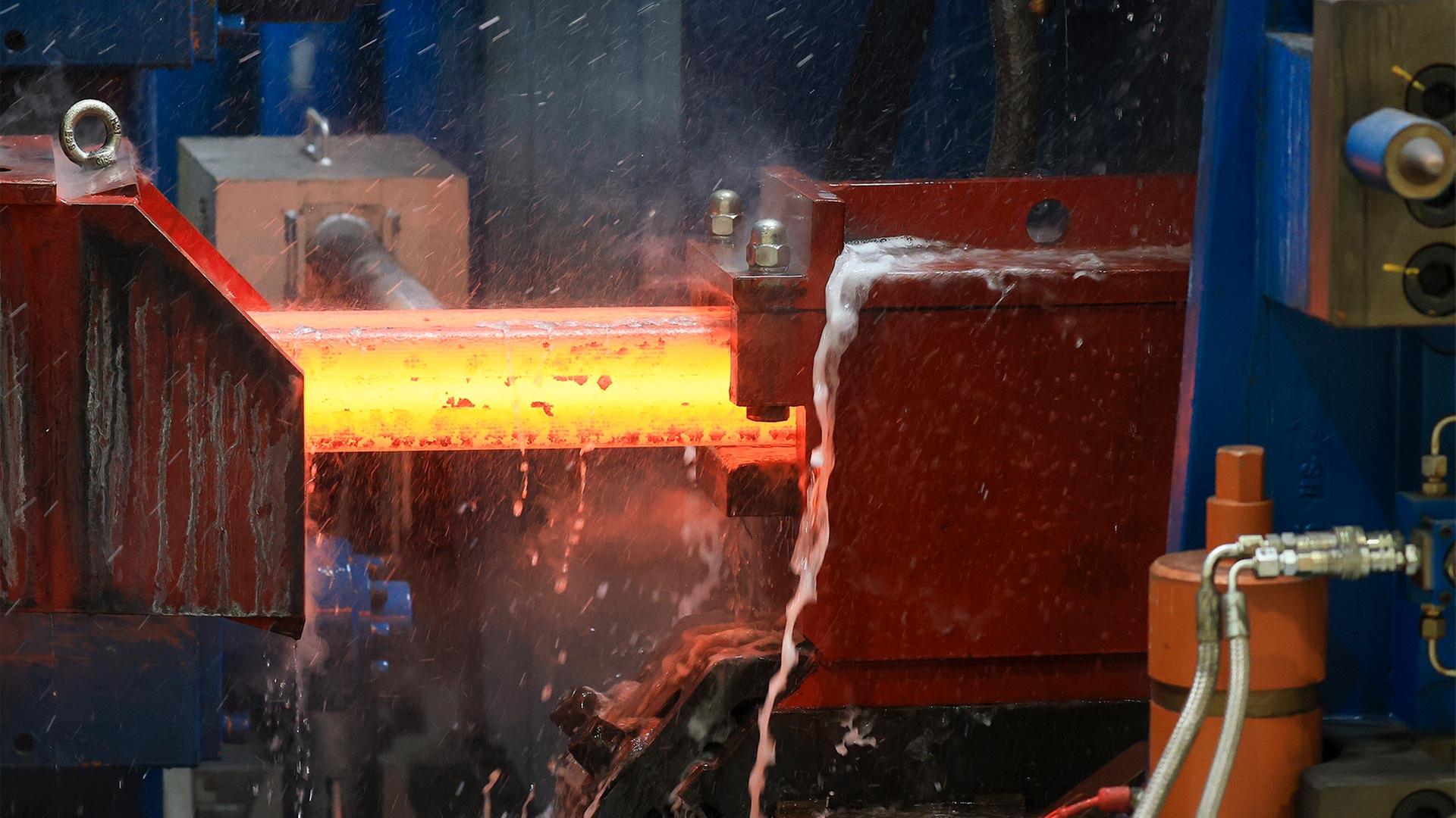 Ein noch glhender Knppel Stahl fhrt ins Walzwerk. | picture alliance/dpa