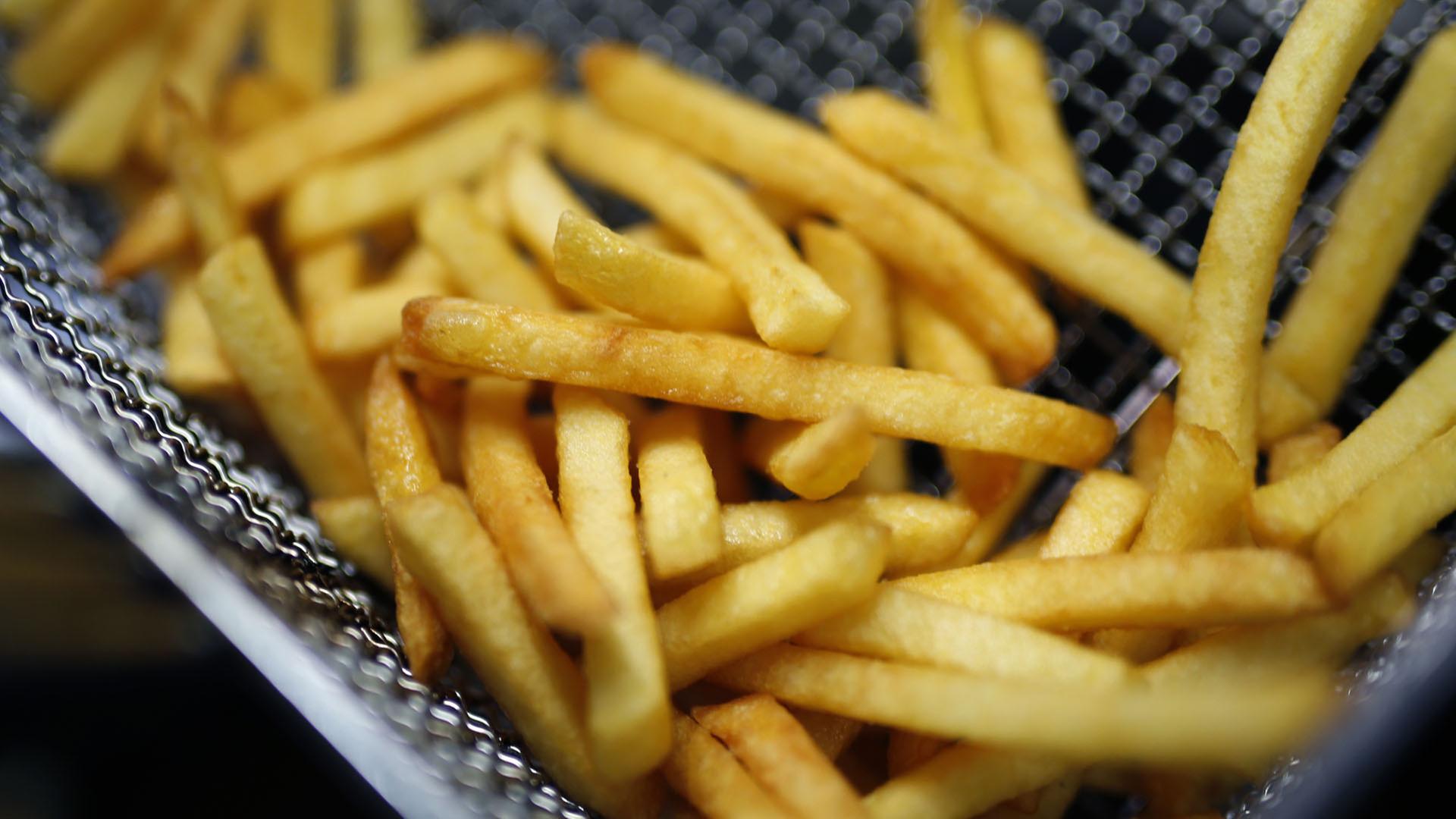 Pommes frites liegen in einer Fritteuse. | dpa-tmn