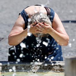 Eine Frau erfrischt sich an einem Brunnen in Rom.