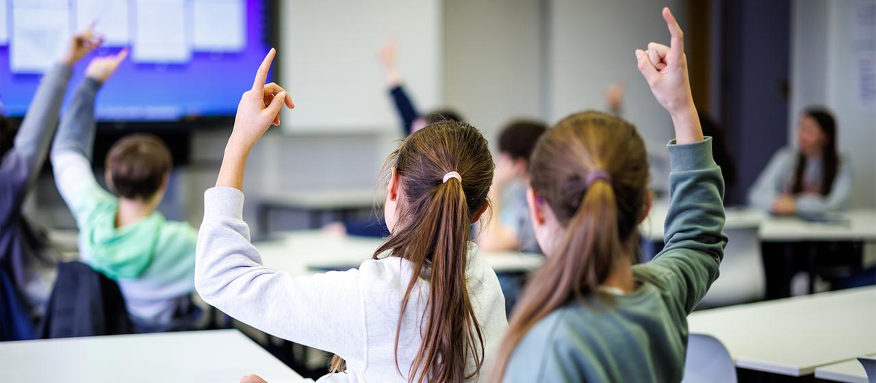 Schülerinnen einer siebten Klasse melden sich in einer Unterrichtsstunde.