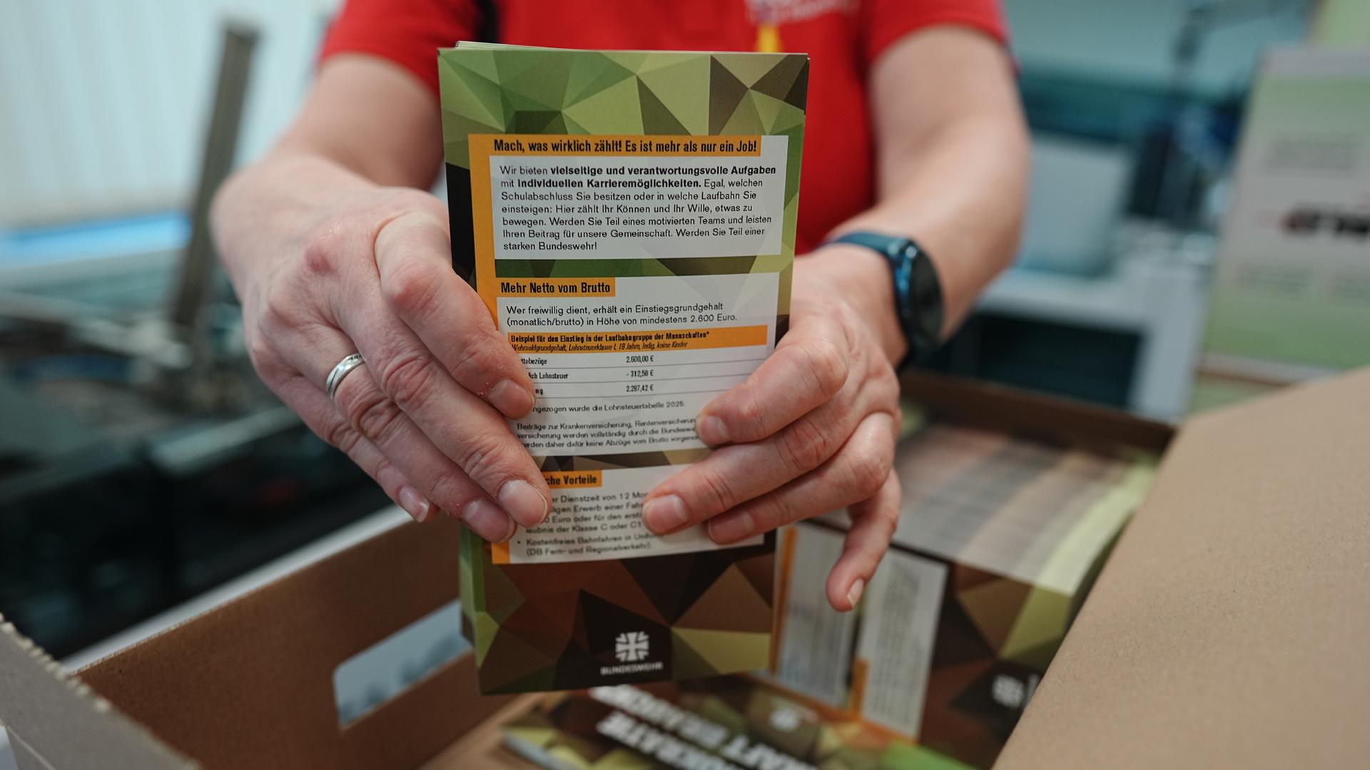 Mitarbeitende sortieren die ersten Briefe mit Broschüren für den neuen Wehrdienst.  | dpa