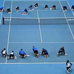 Mitarbeiter und Freiwillige helfen beim Trocknen eines Platzes bei den "Australian Open"-Tennisturniers in Melbourne.