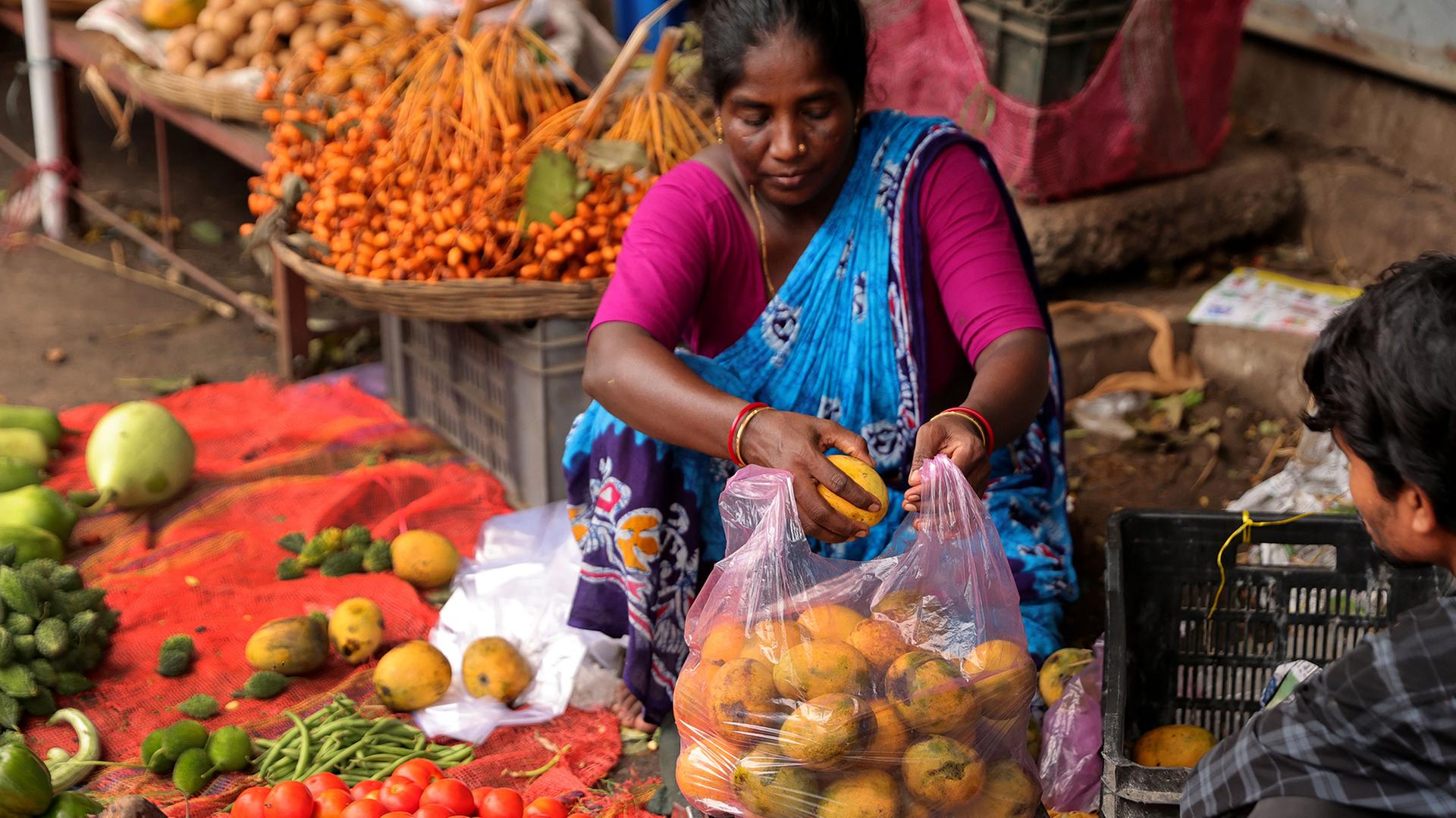 Eine indische Verkäuferin verpackt Mangos in einer Plastiktüte auf einem Markt in Kalkutta.