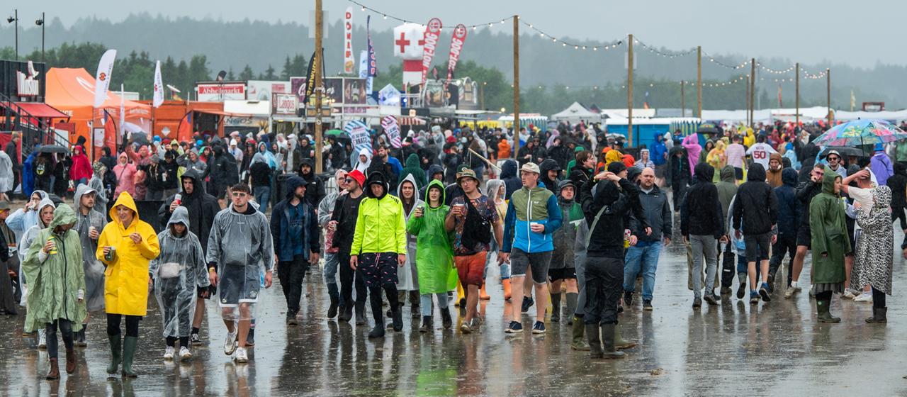 Besucherinnen und Besucher des "Southside"-Festivals in 	Neuhausen ob Eck während eines Regenschauers 