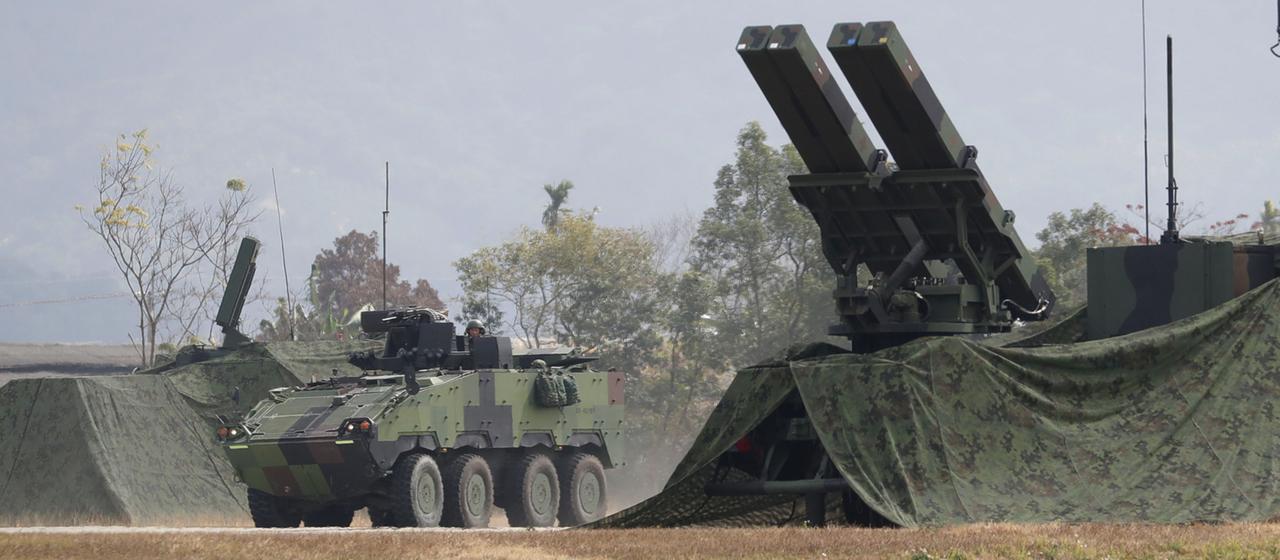 Ein Panzerfahrzeug fährt während einer militärischen Übung in Taichung County, Taiwan,  an einer Mehrfachraketenabschussvorrichtung vorbei.