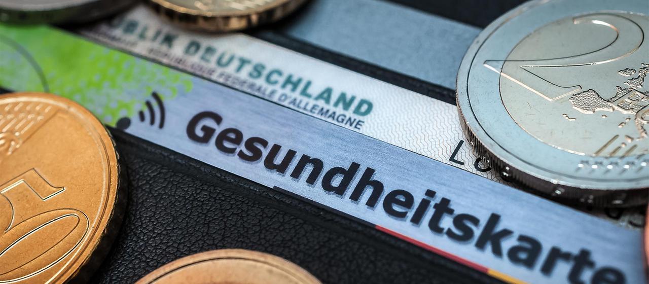 Krankenkassen-Chipkarte und Euromünzen.