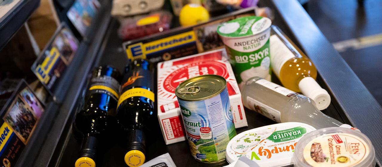Lebensmittel liegen in einem Supermarkt an der Kasse auf dem Band.