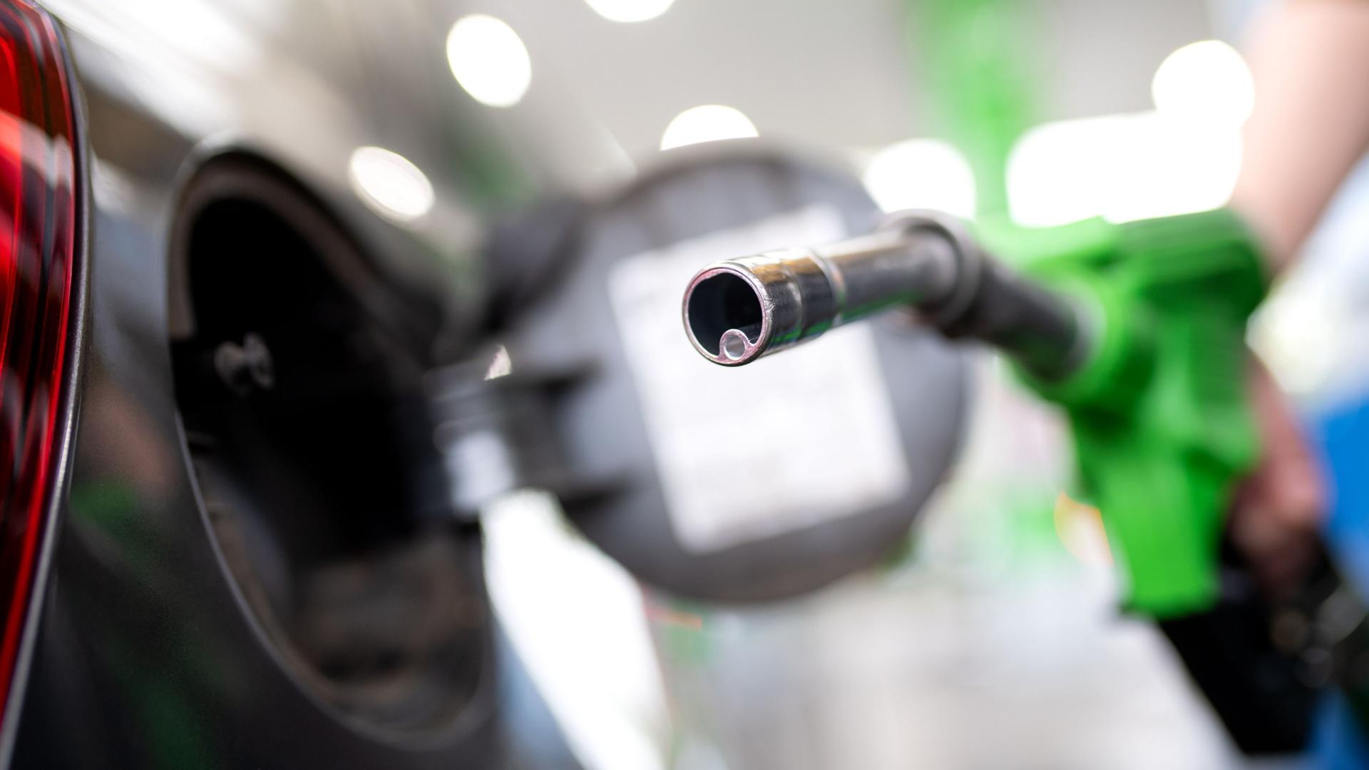 Eine Frau hält an einer Tankstelle an einer Zapfsäule eine Zapfpistole in der Hand. | Sven Hoppe/dpa